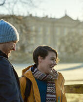 Couple smiling and standing in winter sunshine in front of a country house
