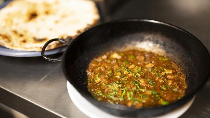 Eine Eisenpfanne mit Curry und Naan-Brot