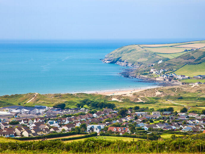 A clear view of a village from above and bay across mountains and out to the ocean