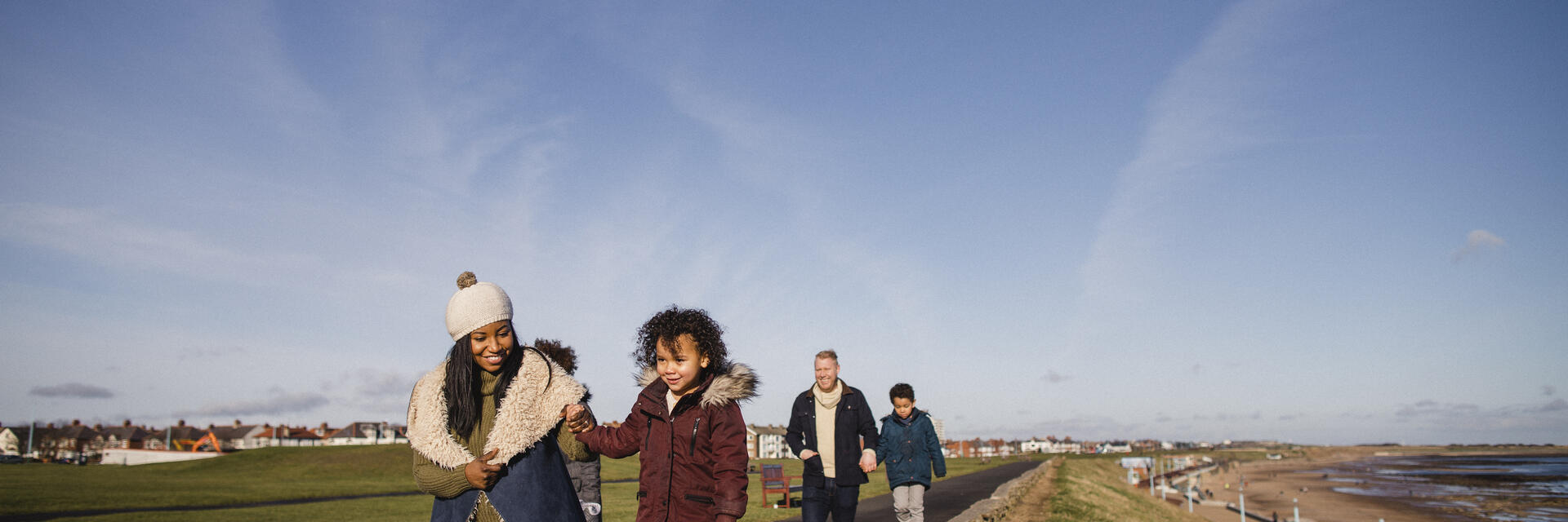 Famille marchant sur un sentier le long de la côte par une journée ensoleillée avec ciel bleu