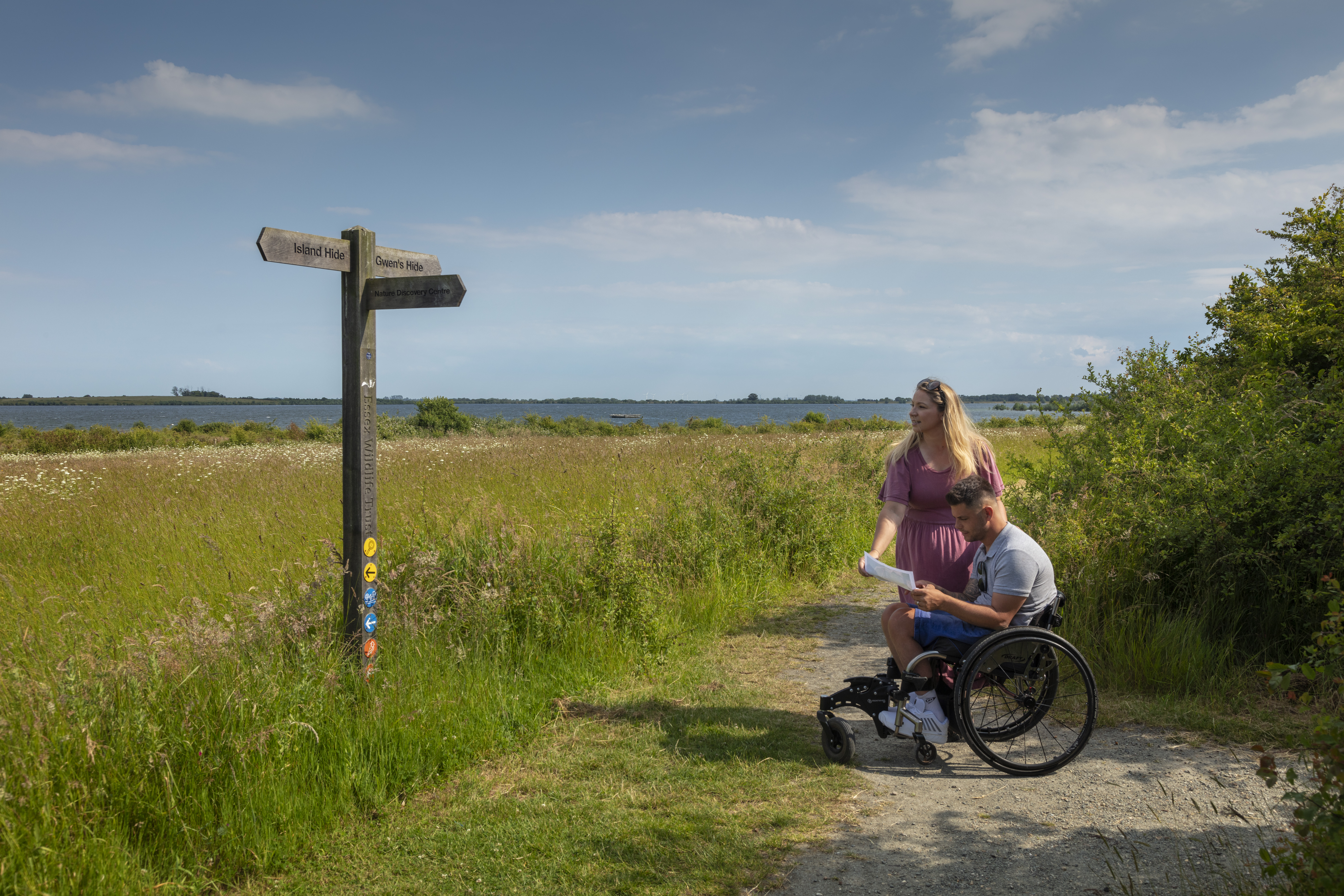 A man who uses a wheelchair and a woman review a map in the countryside