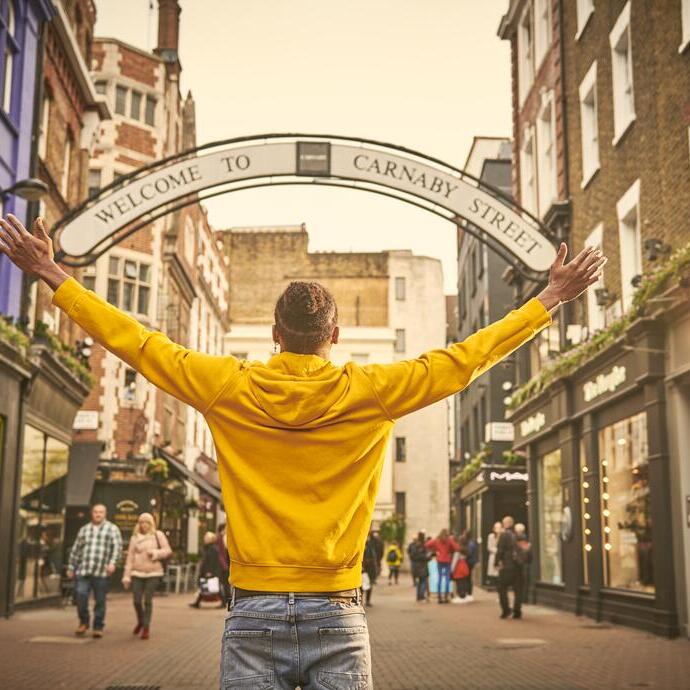 Man standing with arms outstretched on a street