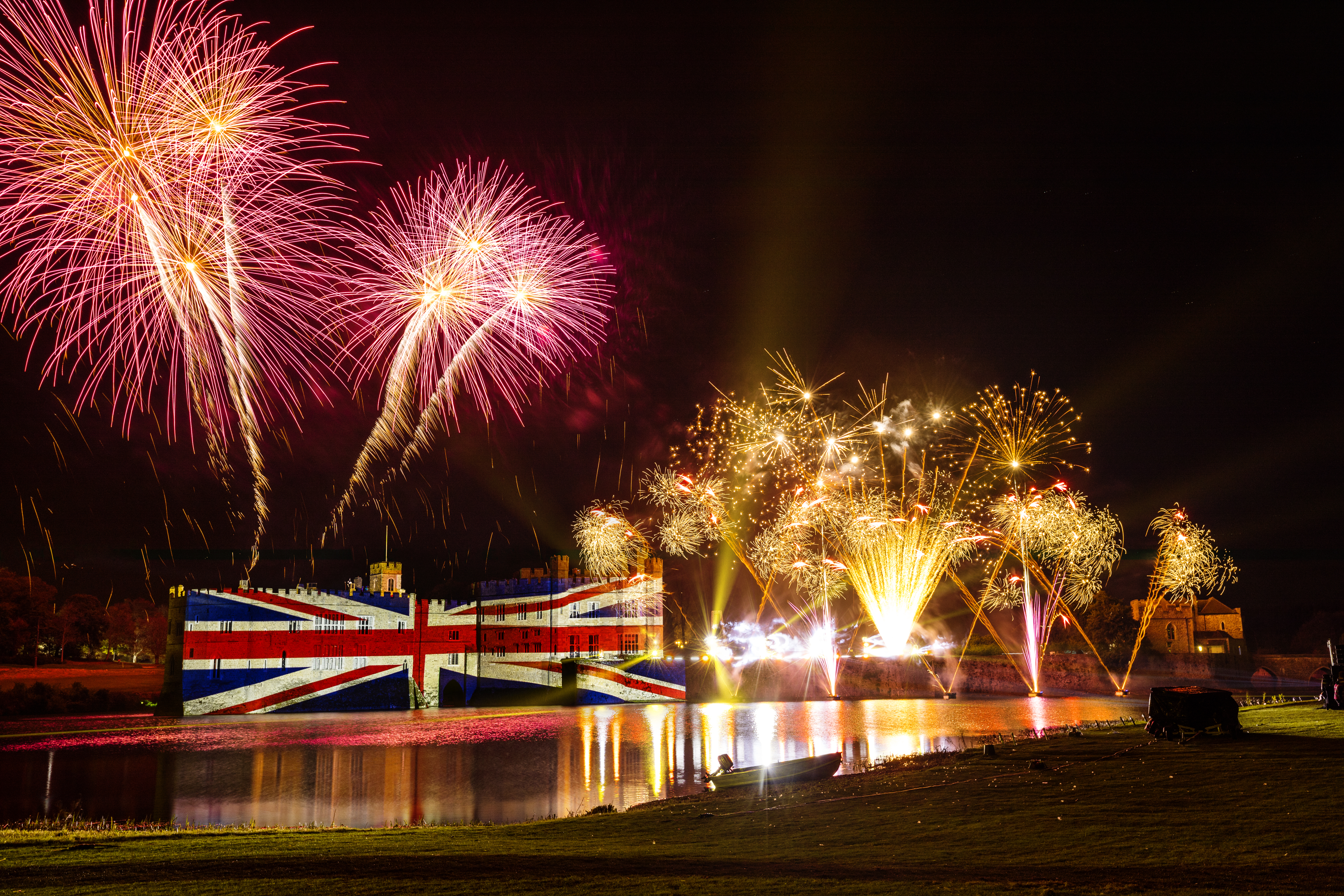 Feuerwerk und eine große Union-Jack-Beleuchtung auf einer Burgmauer bei Nacht