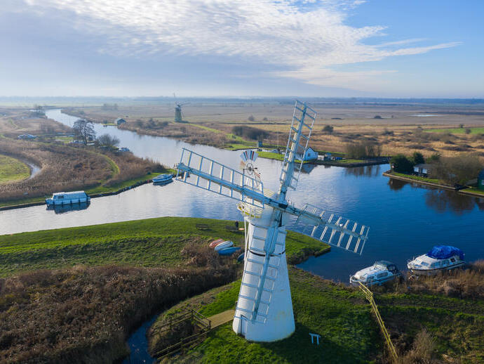 Aerial view of a windmill and surrounding pasture and canals 