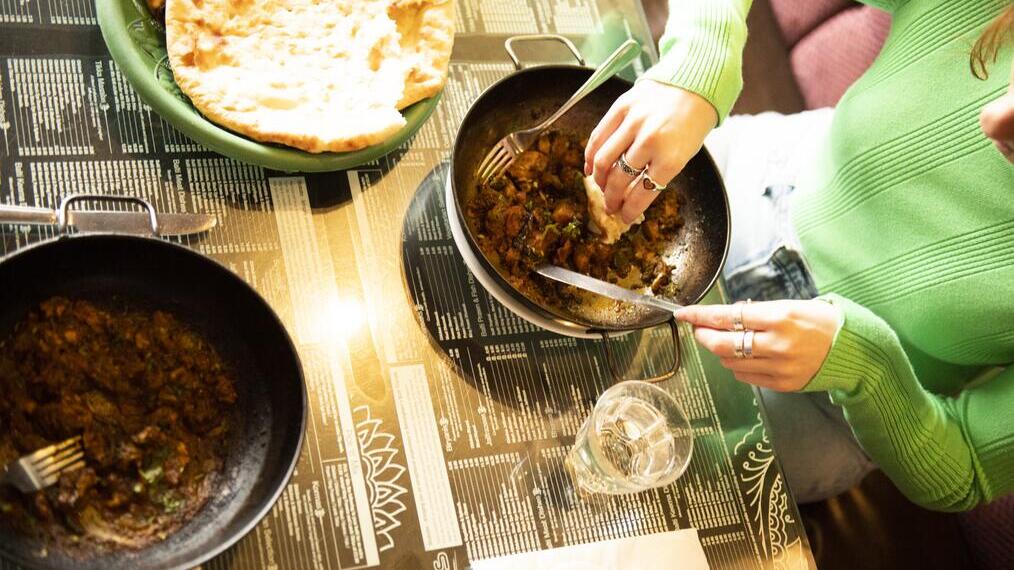 A curry dish and naan bread on the side served at a restaurant