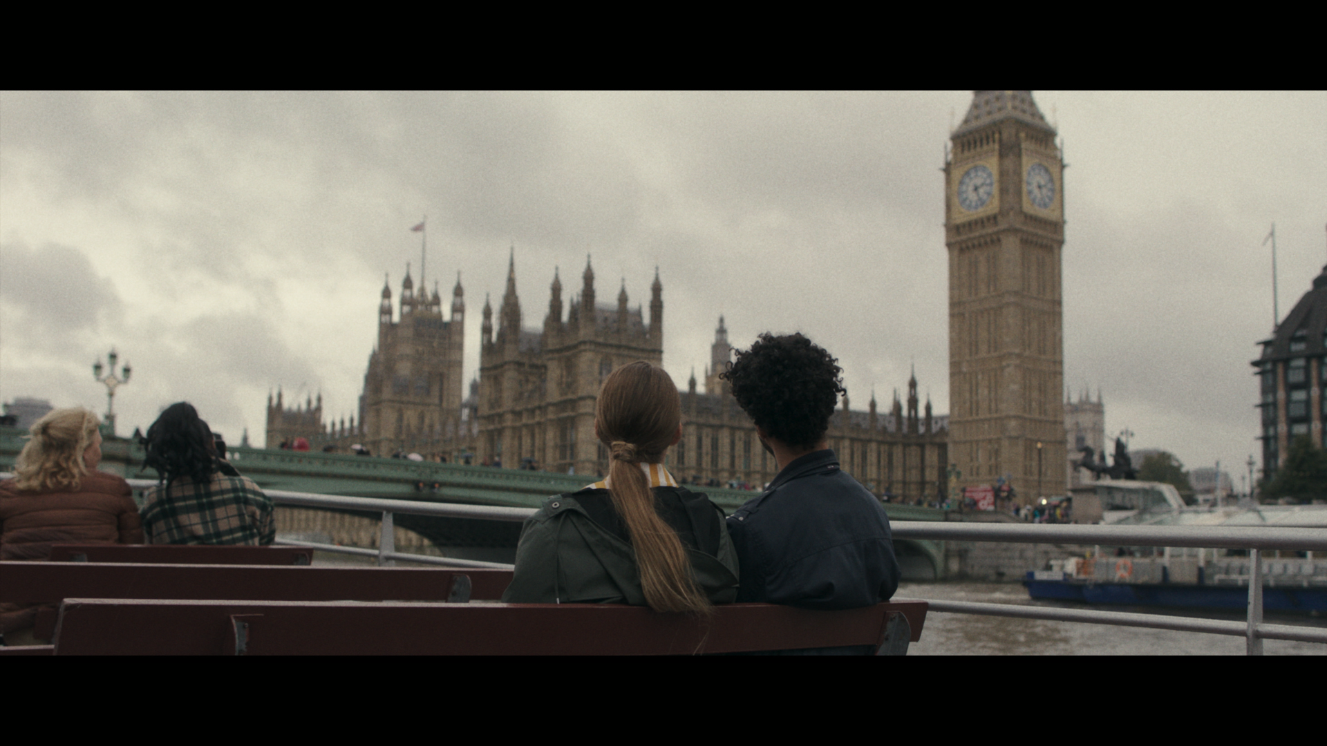 A group of people take a trip on a river boat with the Houses of Parliament beyond