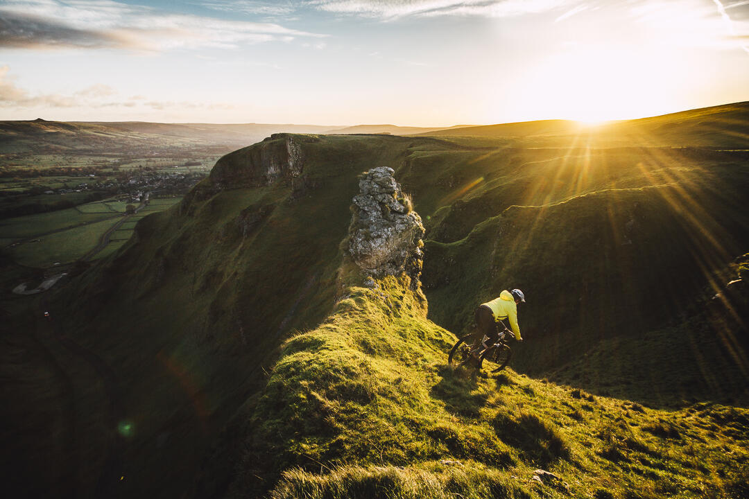 Cyclist riding down a steep hill at sunset