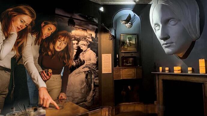 Dimly lit museum exhibit with historical images, a large sculpted face, candles, and people examining artifacts and displays.