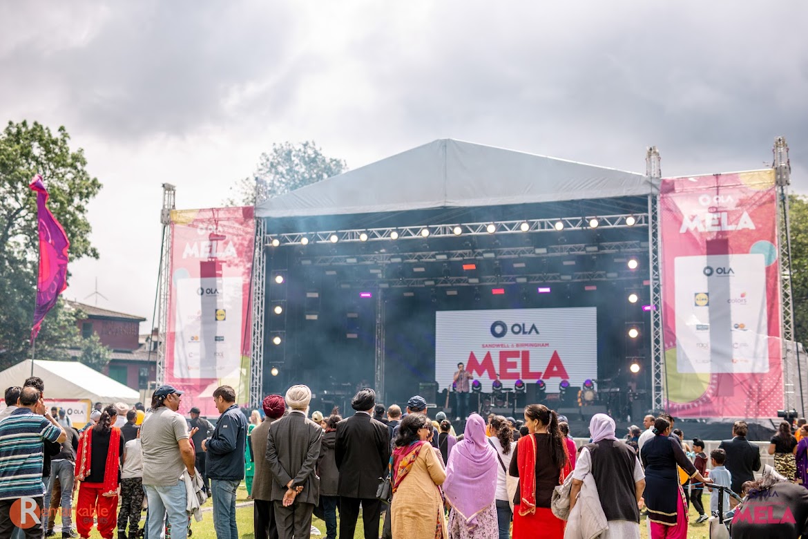Crowd of people in front of a stage at the Mela Festival watching a performance