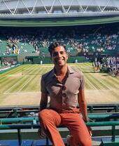 Un hombre sentado en una silla en una de las pistas del campeonato de tenis de Wimbledon