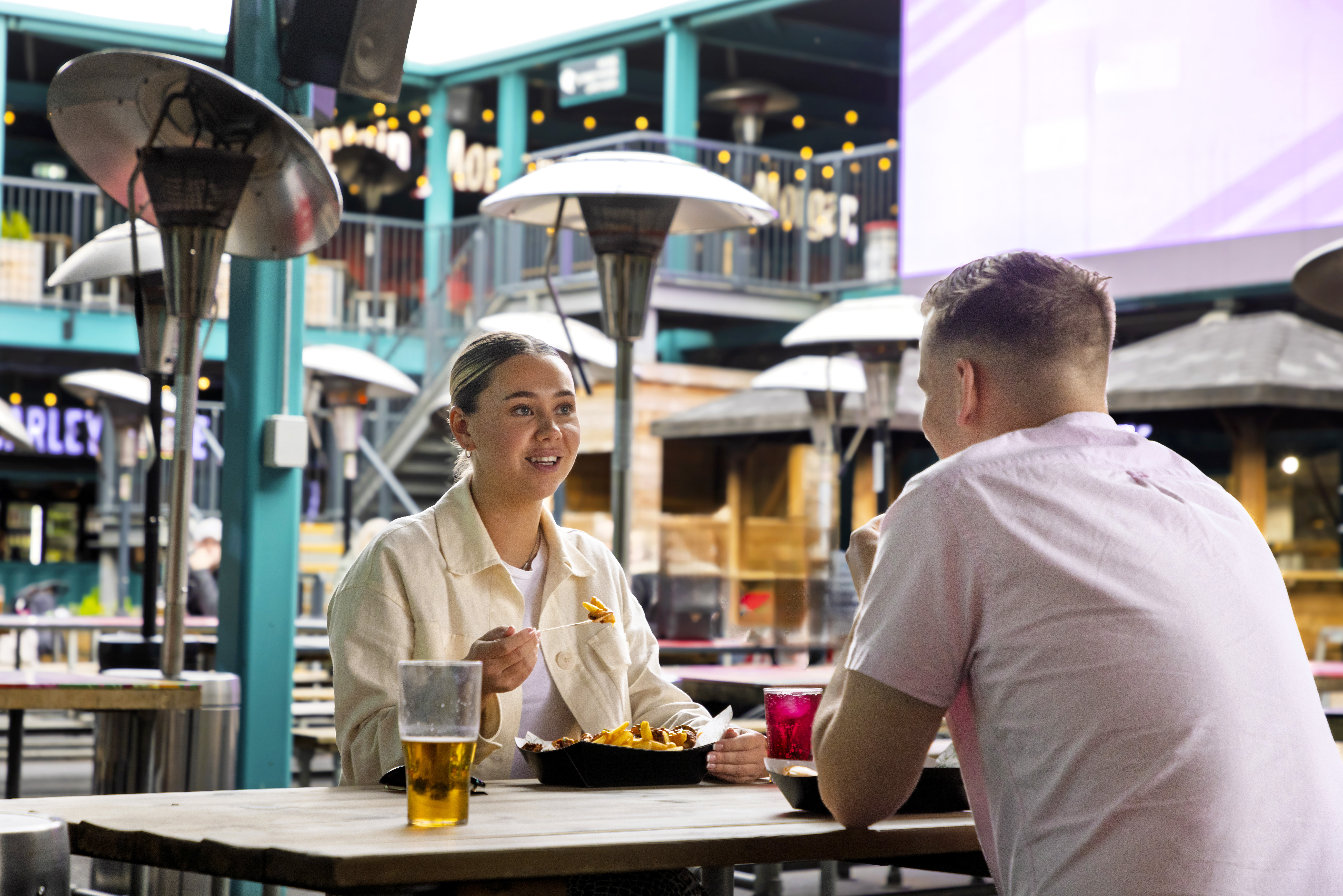 Two people enjoying food and drinks at an outdoor cafe.