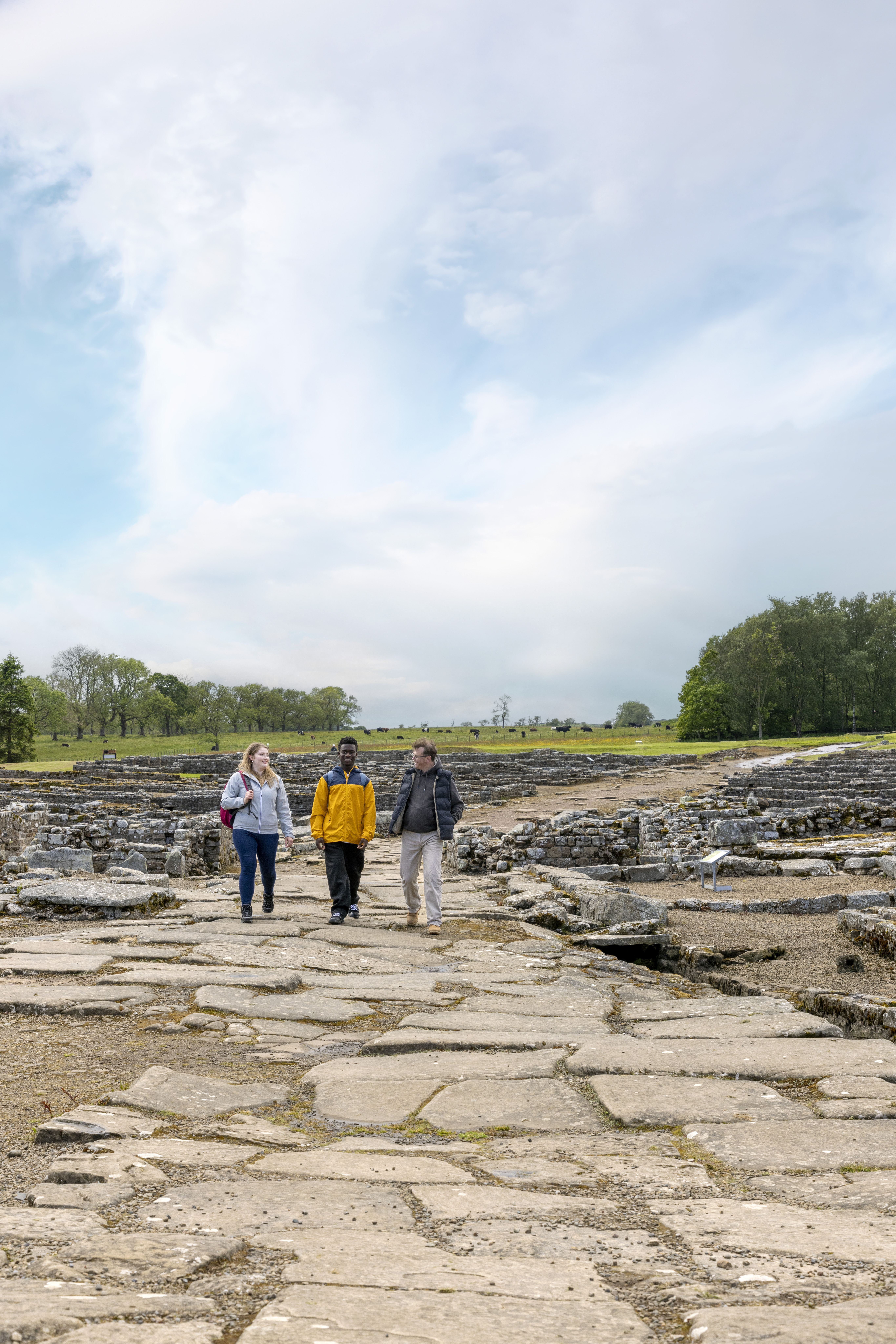 Three people walk among ancient ruins