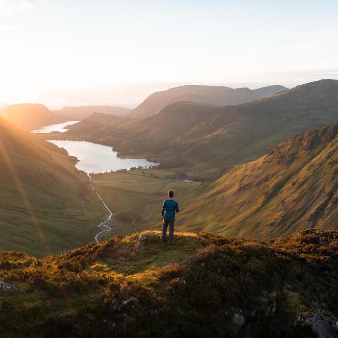 A man stands looking out over a vast lake view