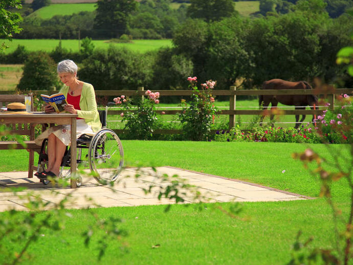 Woman in a wheelchair in the garden, reading