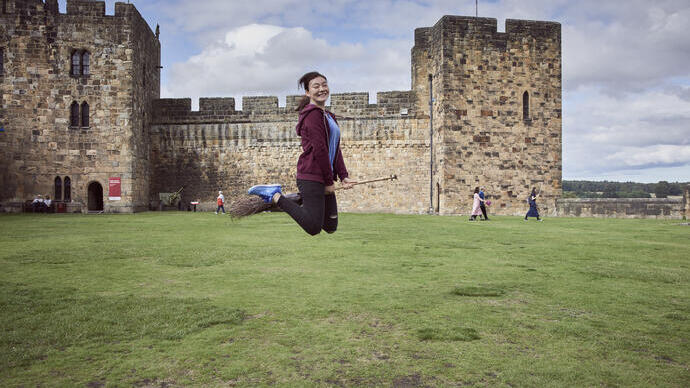 Woman on a broomstick outside a castle