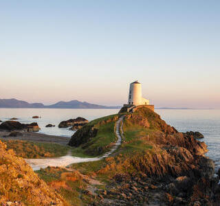 A path leading to a lighthouse on a prominent rocky outcrop by the sea