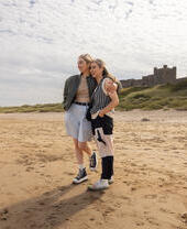 Zwei Frauen umarmen sich am Strand in der Nähe einer Burg