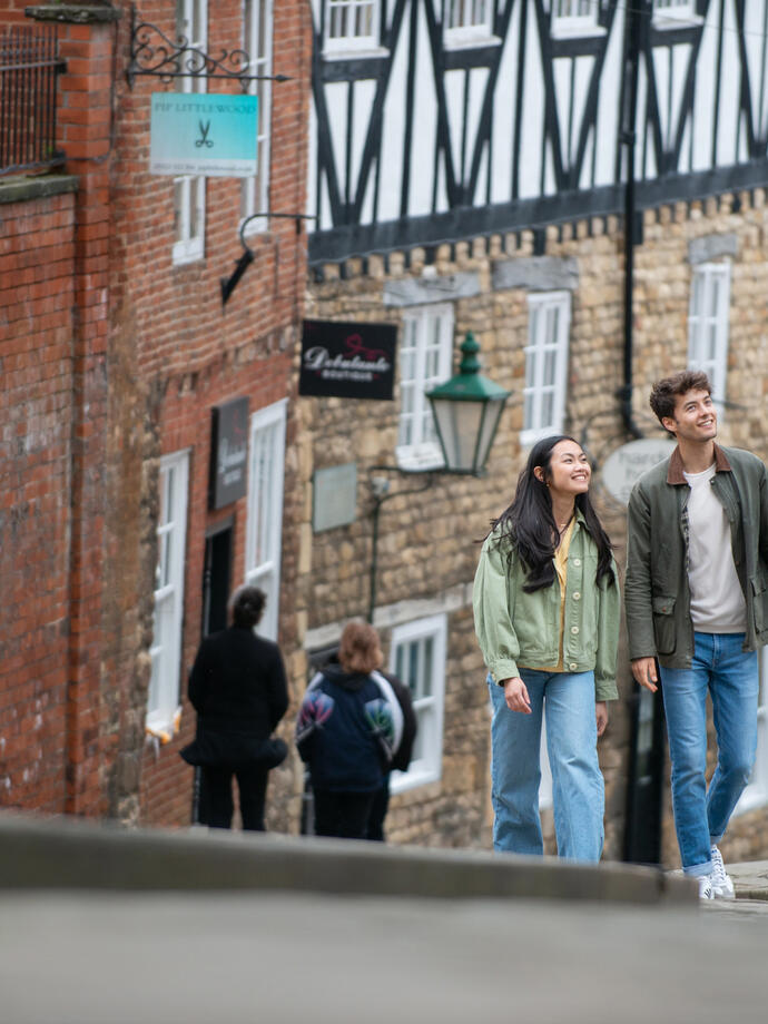 A woman and a man walk up a steep hill in a heritage City