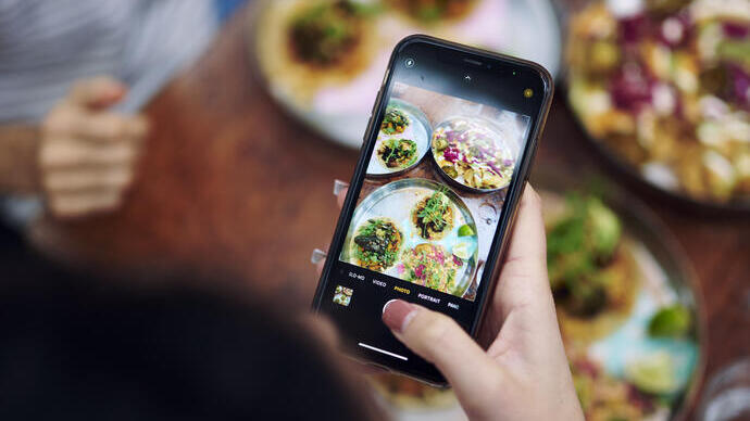 Woman taking a photo on her mobile phone of food on the table in a restaurant
