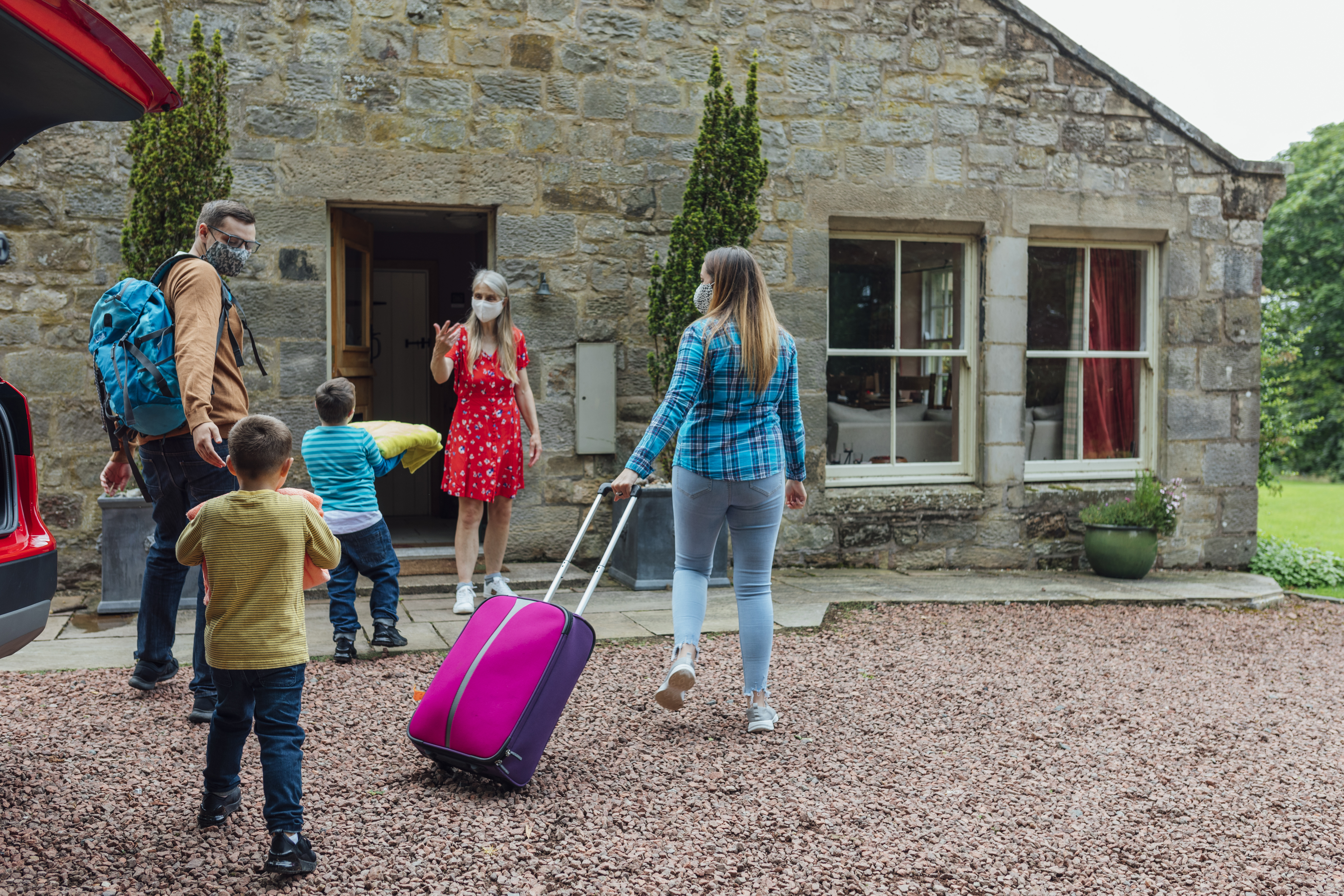Family arriving at a Bed and Breakfast home, met by the owner