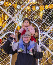 Mann mit einem kleinen Mädchen auf den Schultern vor Lichtern