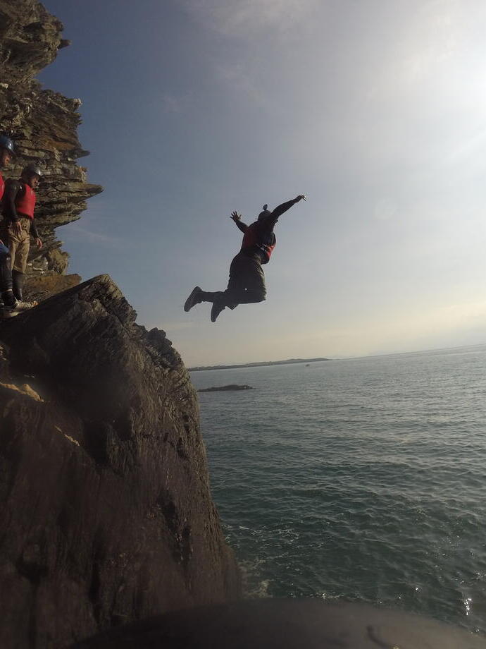 Un grupo de personas saltando desde unos acantilados bajos al mar cerca del Parque Nacional Snowdonia/Eryri