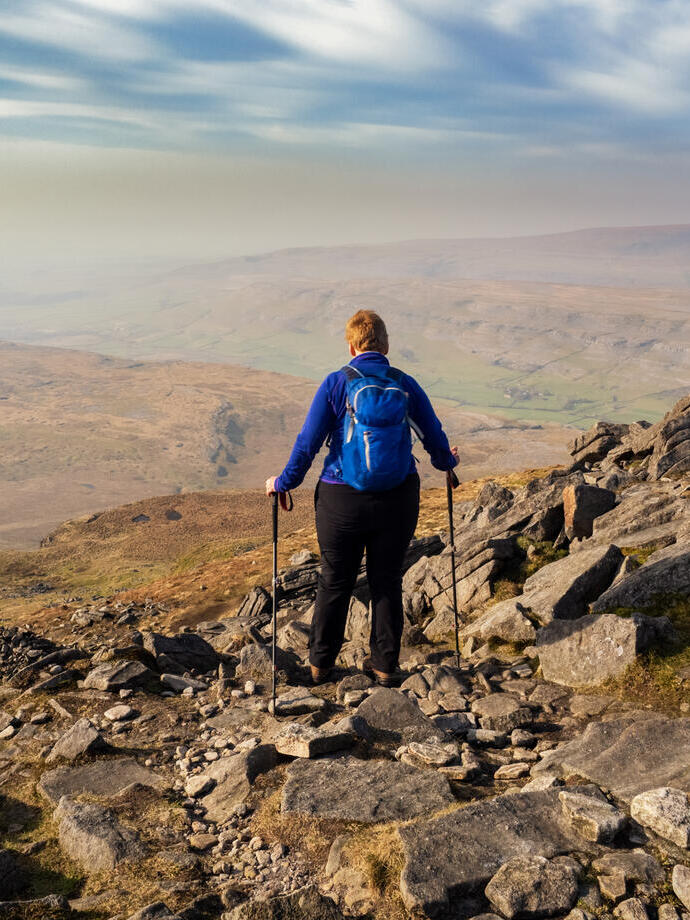 Hiker navigating across a rocky descent on a high mountain with walking poles