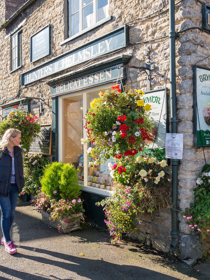 Two women walking past a shop in a village