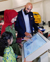 A family looking at an interactive exhibit at the British Motor Museum