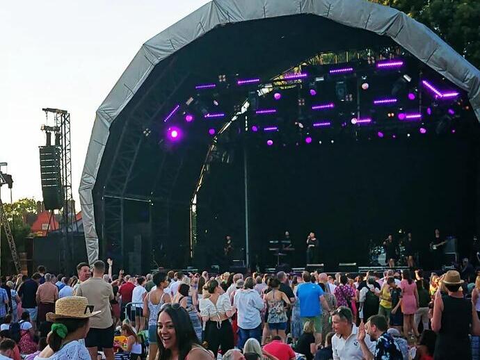Crowd of people enjoy an evening concert at Kew Gardens.