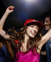 A woman dancing with her hands up in a nightclub.
