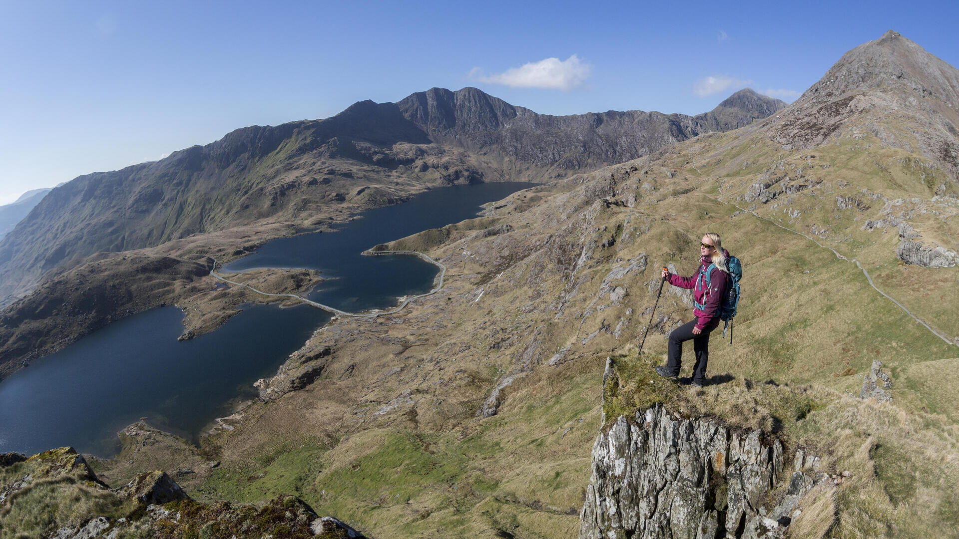 Woman standing on a rock, high above the lake in a valley