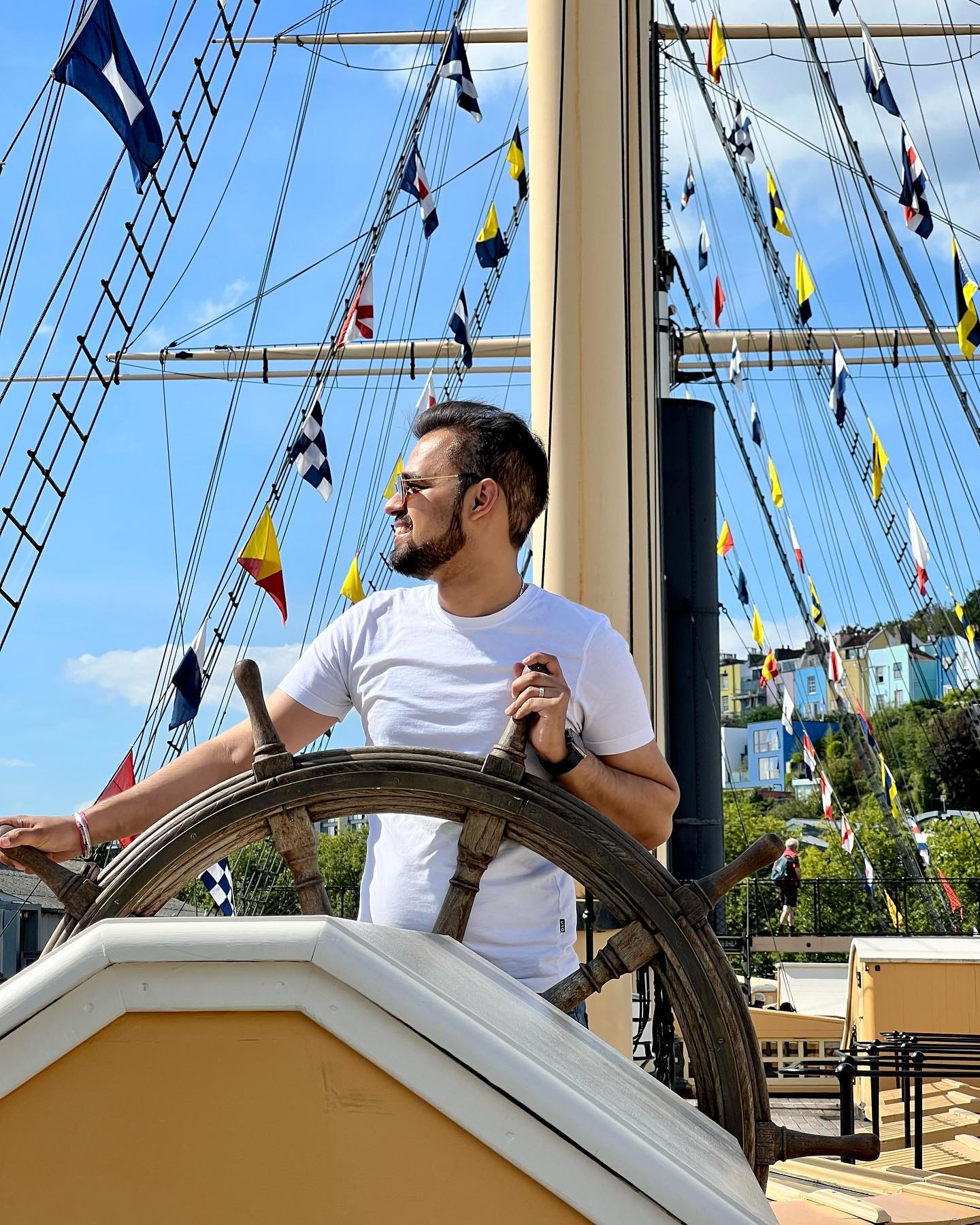 A man stood at a ship's wheel in the harbourside of Bristol