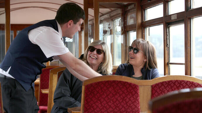 Railway passengers on a heritage train talking to crew member.
