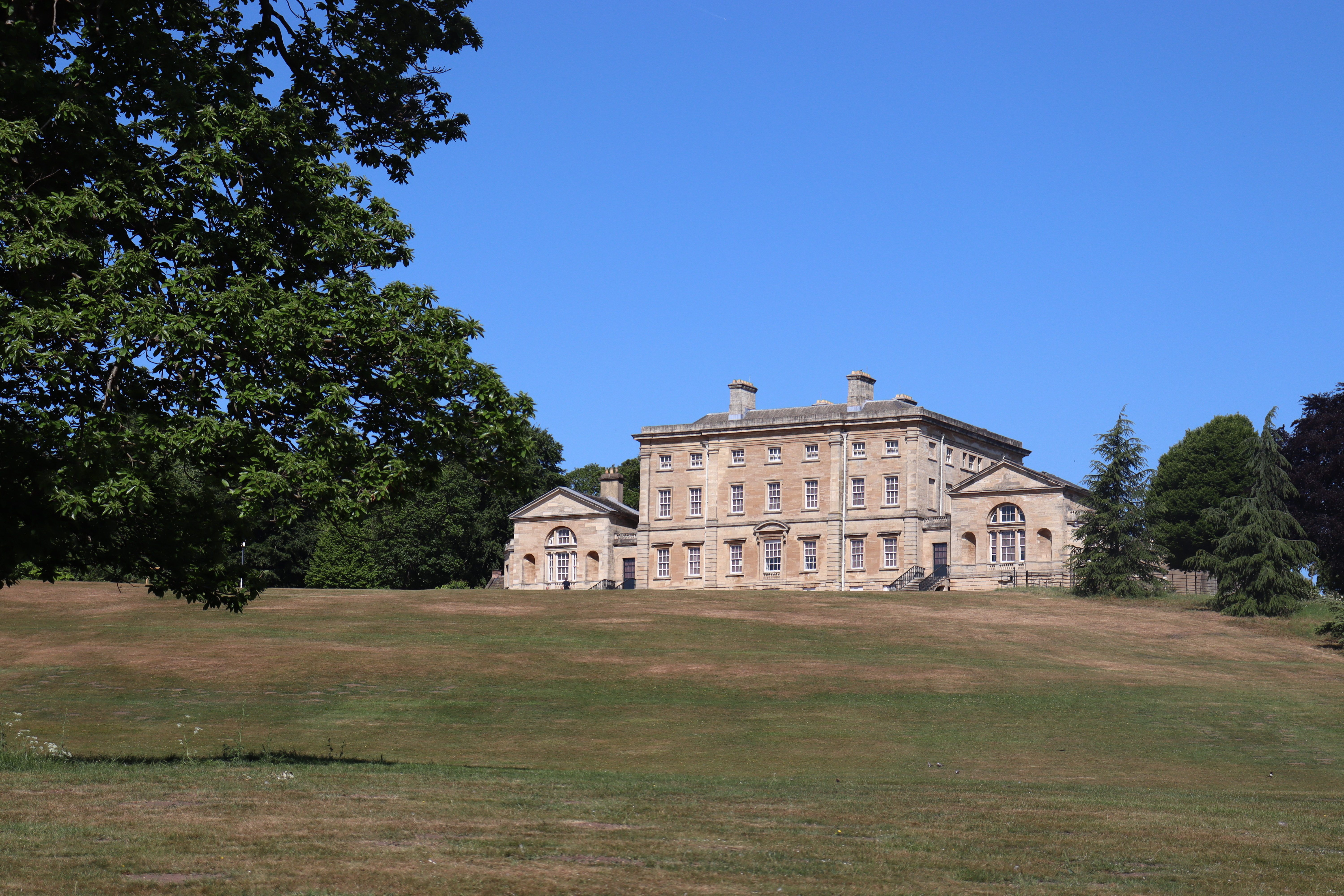 View of a large country house surrounded by trees