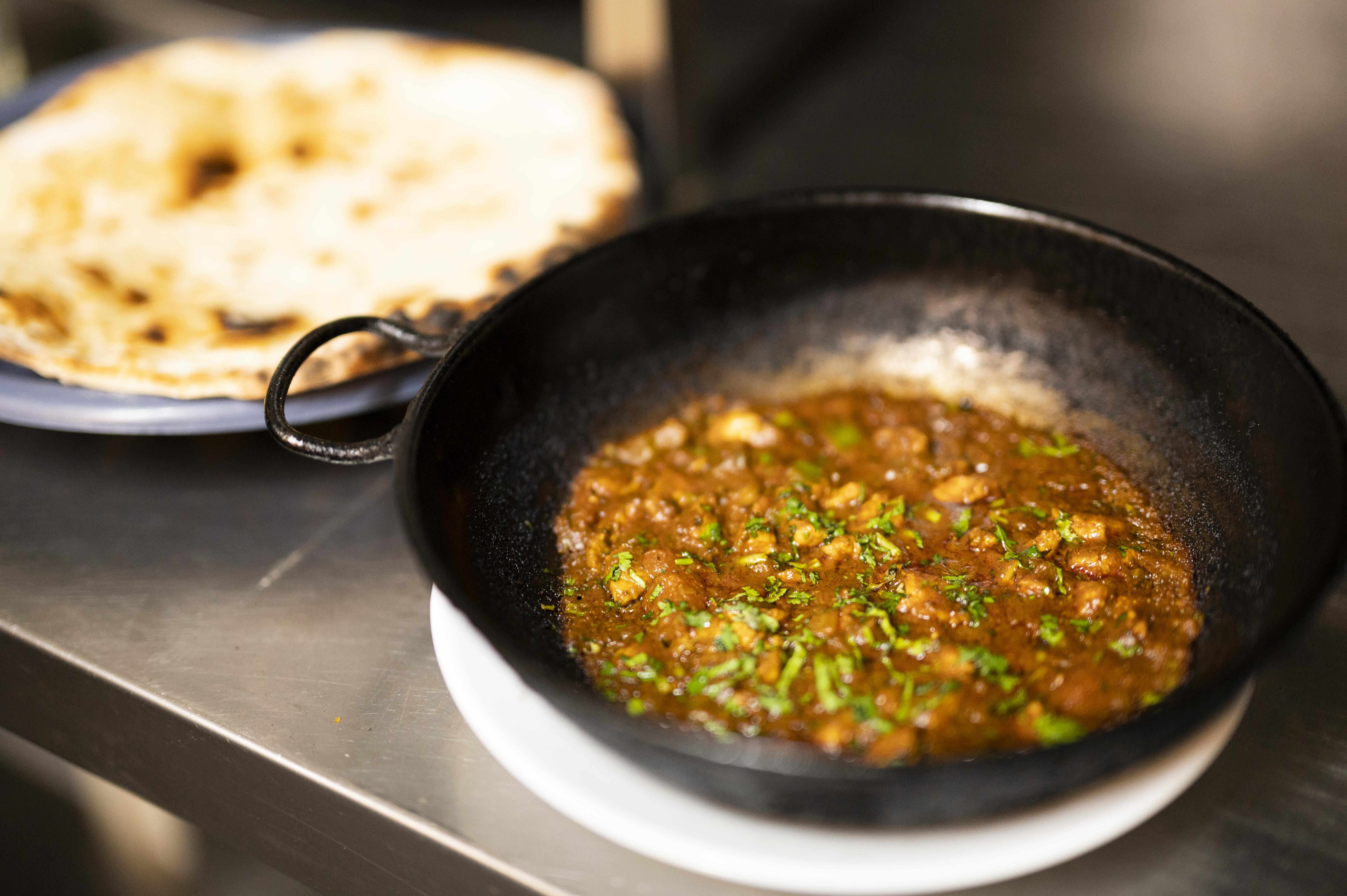 Una padella di ferro piena di curry e pane naan