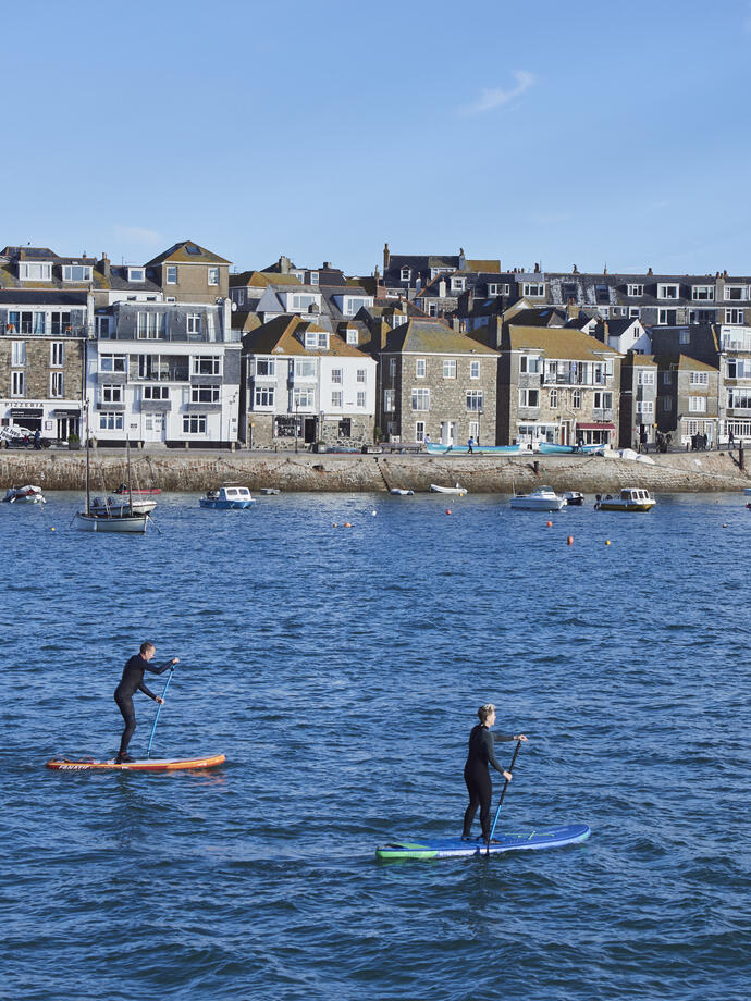 Two people on paddle boards floating in a harbour