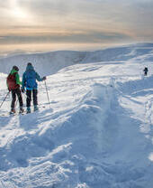 People skiing in the snow on a mountain ridge