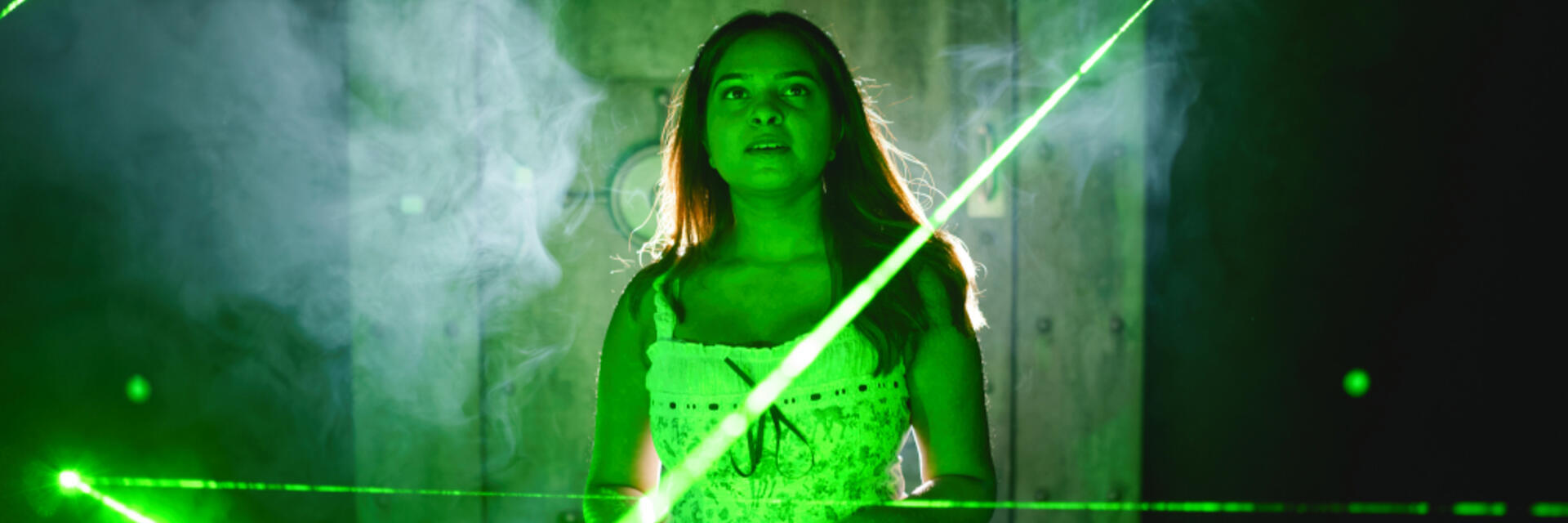 Una donna si diverte con l'esperienza laser interattiva di una escape room.