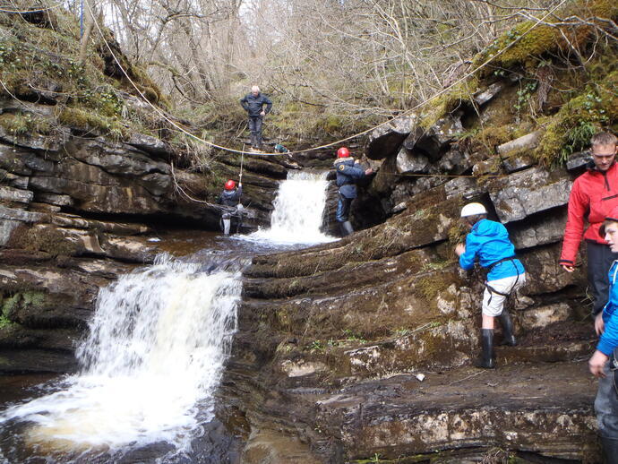 Children using a zipline across a waterfall at Alternative Adventure in Lancashire