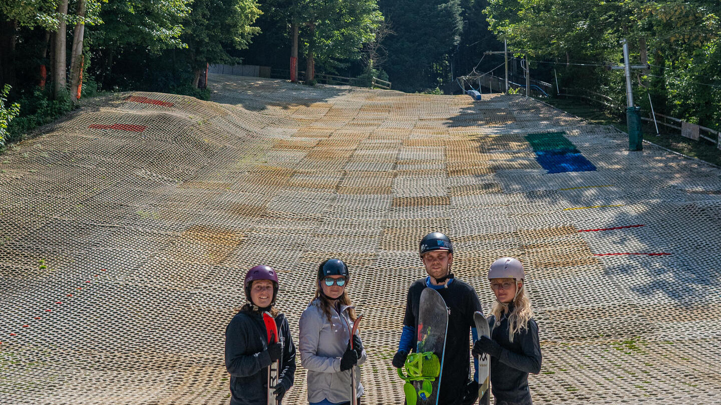 A group of people posing with skis at a dry ski slope