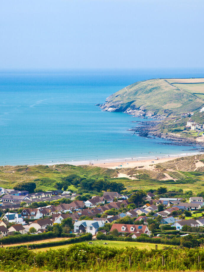 A clear view of a village from above and bay across mountains and out to the ocean