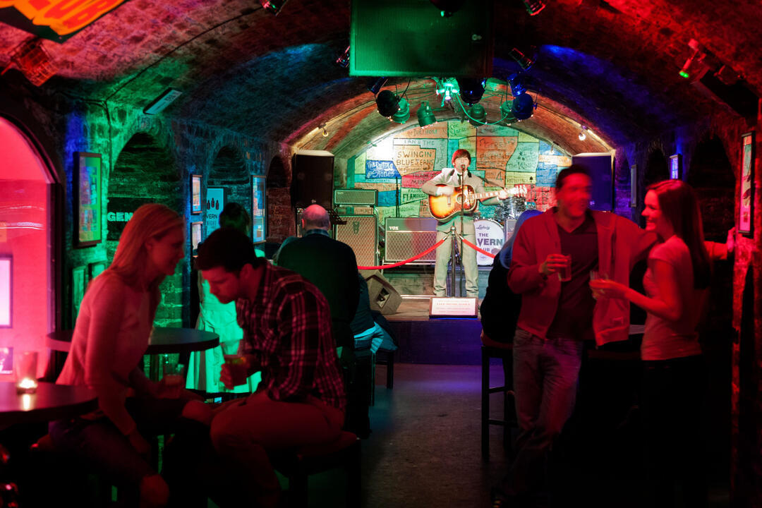 رجل على خشبة المسرح يعزف على الغيتار في نادٍ ذي سقف مقوس