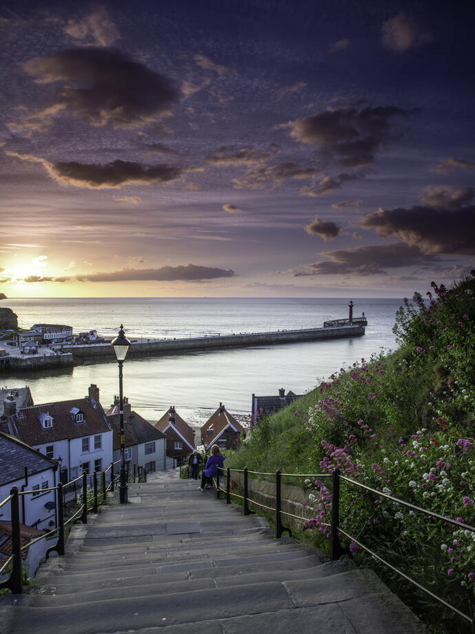 Two people on the steps of a cliff by the sea