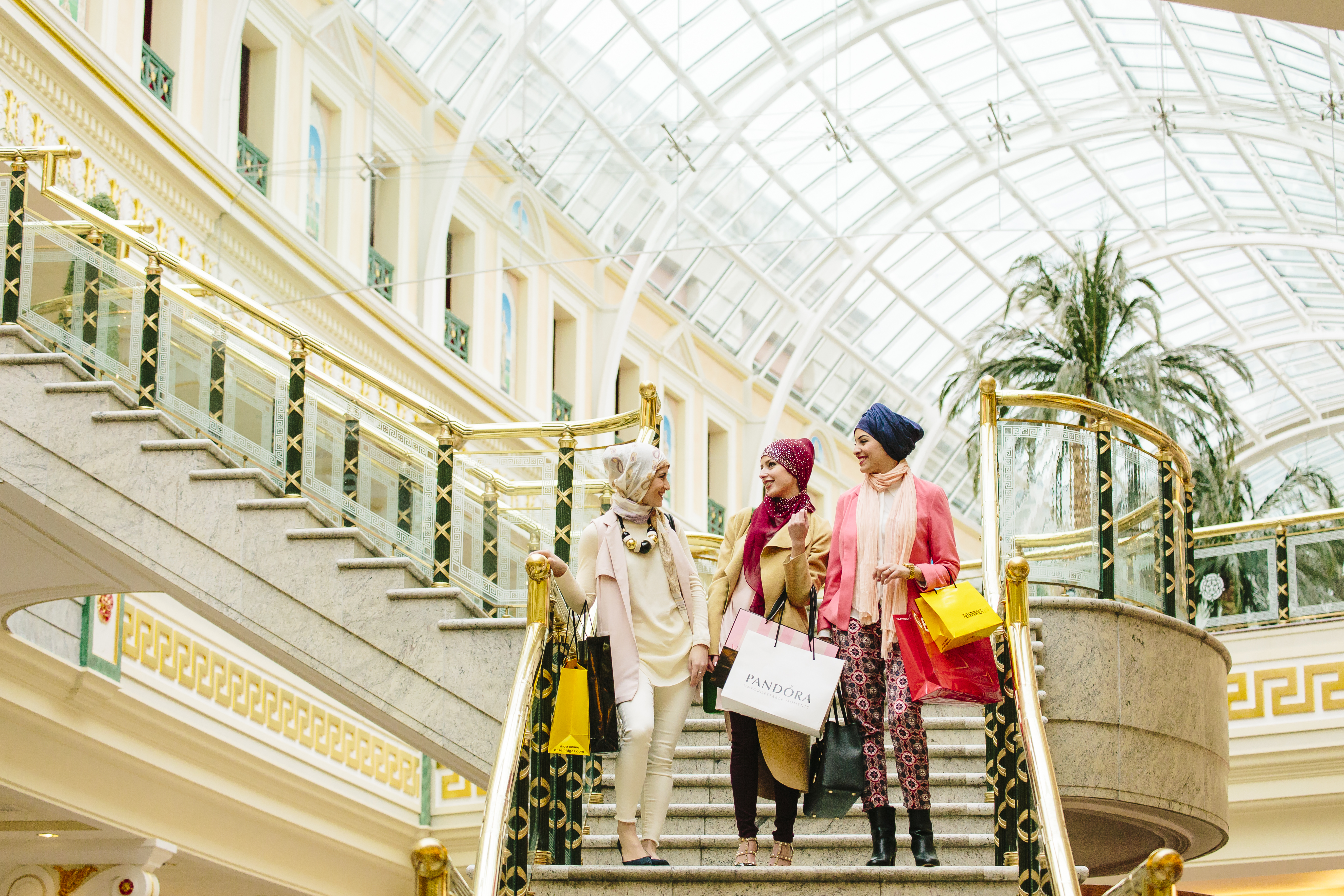 Tres mujeres con bufandas caminando con bolsas de la compra