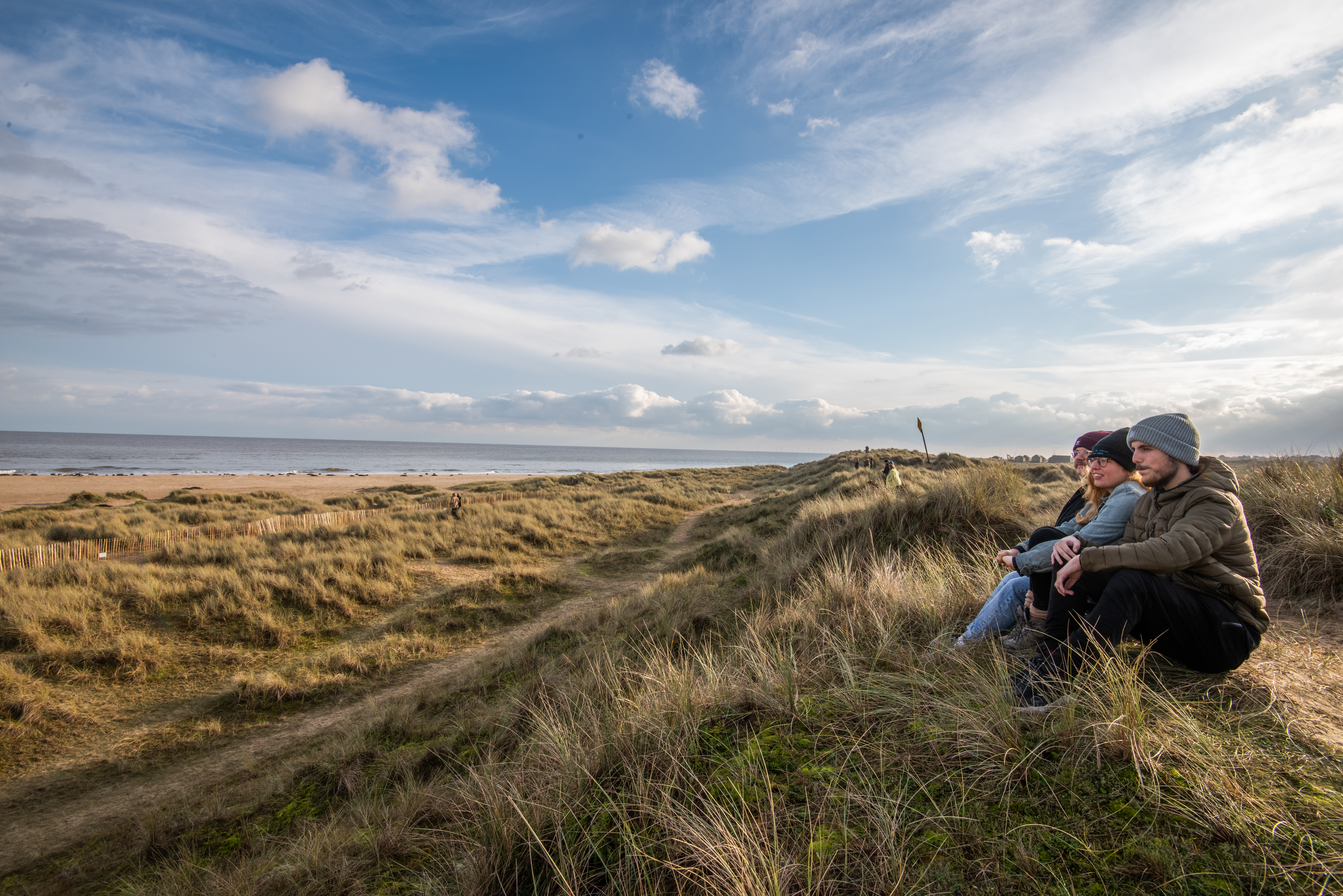 A group of people looking out at the sea from Winterton Dunes
