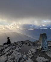 A man sitting at the top of Ben Lomond mountain