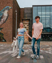 A couple walking past street art outside a museum