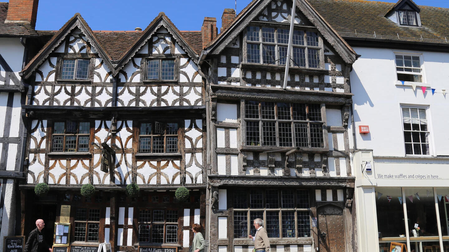 Street level view from across the street of pedestrians walking by The Garrick Inn, a half timbered frame 16th Century building in Stratford Upon Avon, ruputed to be Stratford's oldest pub.