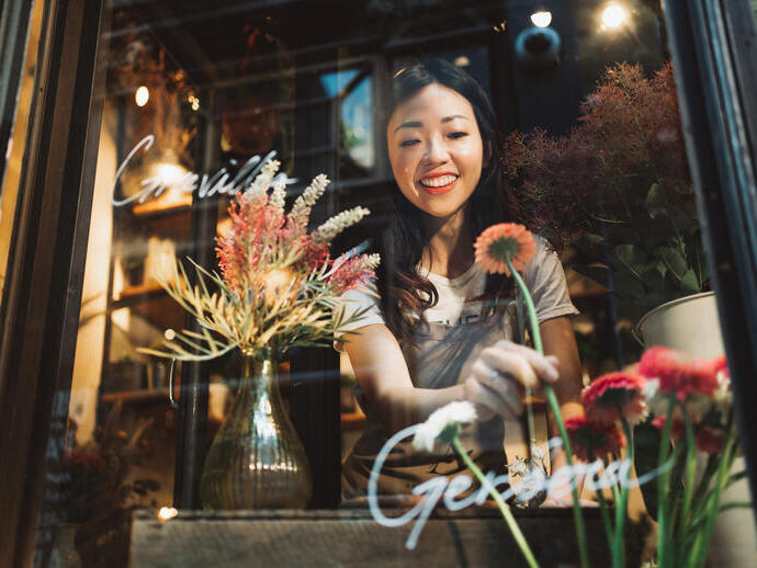Asian young florist working on the arrangement of flowers for her shop.